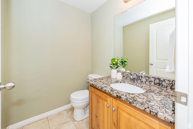 half bath featuring toilet, tile patterned floors, vanity, and baseboards
