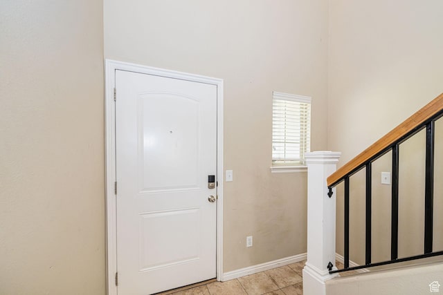 foyer entrance with light tile patterned floors and baseboards