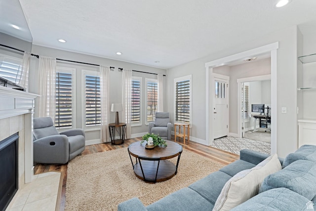 living room featuring baseboards, recessed lighting, light wood-style flooring, and a fireplace