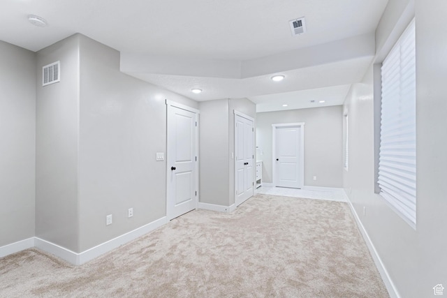 basement featuring visible vents, light colored carpet, and baseboards