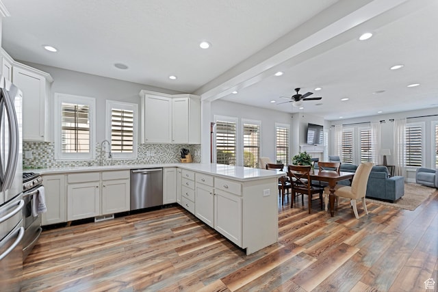 kitchen featuring stainless steel appliances, open floor plan, light wood-type flooring, recessed lighting, and a peninsula