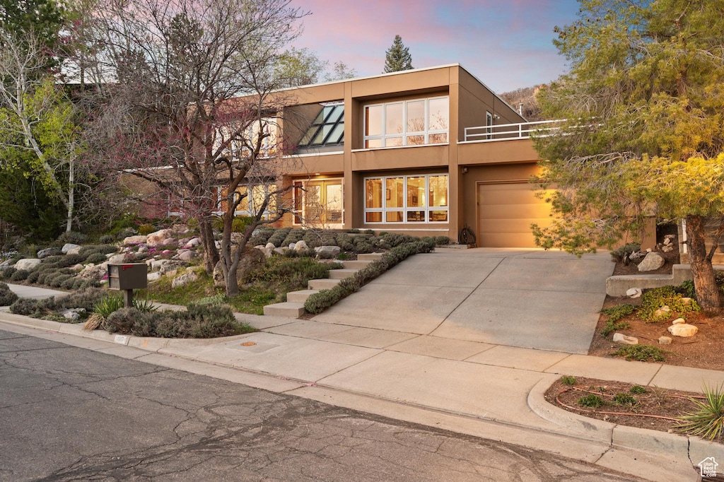 view of front of home with concrete driveway, a balcony, stucco siding, and an attached garage