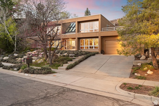 view of front of home with concrete driveway, a balcony, stucco siding, and an attached garage