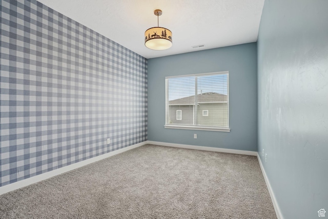 unfurnished room featuring baseboards, wallpapered walls, and carpet