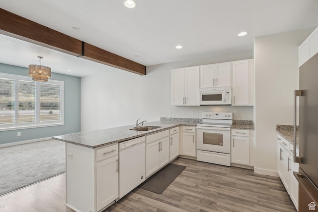 kitchen featuring white cabinets, a sink, white appliances, a peninsula, and light stone countertops