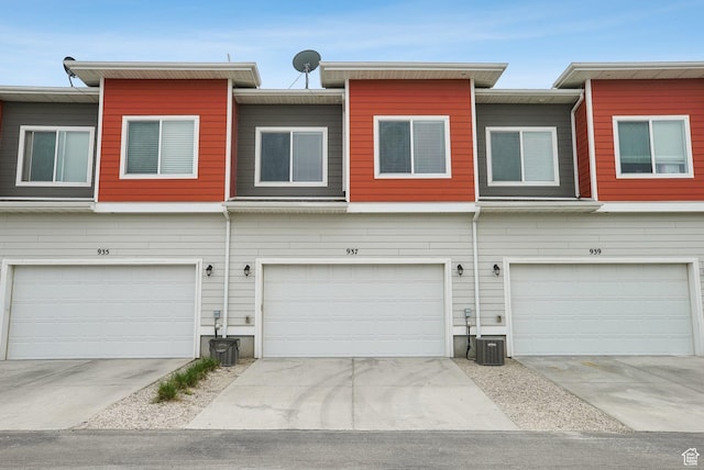 townhome / multi-family property with central AC unit, driveway, and an attached garage