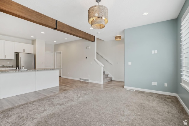 unfurnished living room with recessed lighting, stairway, baseboards, and light colored carpet