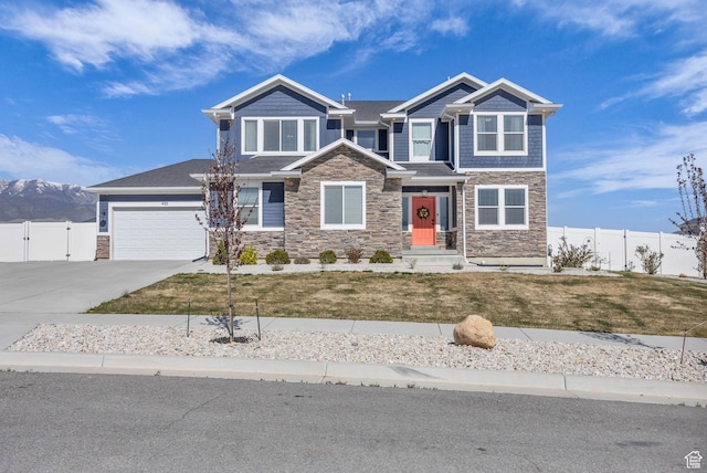 craftsman house with concrete driveway, fence, stone siding, and a gate