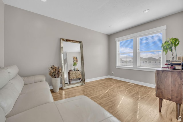 living area with recessed lighting, light wood-style floors, and baseboards