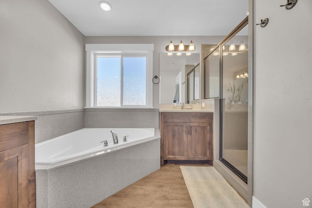 bathroom with vanity, a garden tub, a stall shower, and wood finished floors