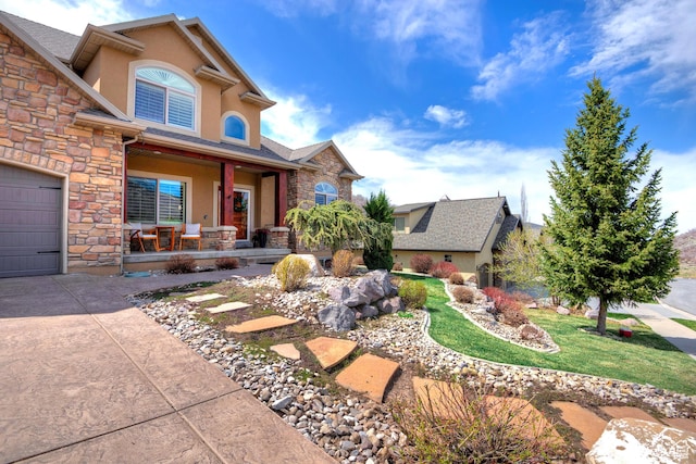 view of front of property featuring stone siding, covered porch, a garage, and stucco siding