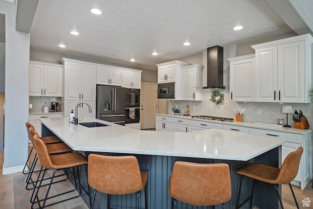 kitchen featuring a sink, wall chimney range hood, recessed lighting, white cabinets, and black appliances