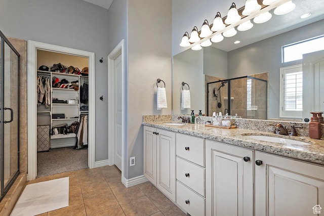 bathroom featuring a sink, a walk in closet, a shower stall, and double vanity