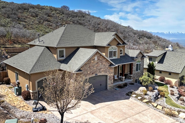 view of front of property with concrete driveway, stucco siding, stone siding, a garage, and covered porch