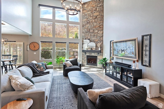 living area featuring a high ceiling, a wealth of natural light, a notable chandelier, and wood finished floors