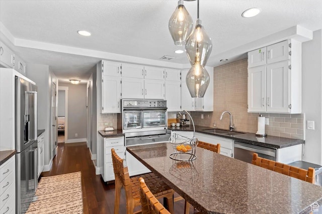 kitchen with appliances with stainless steel finishes, a sink, white cabinetry, and visible vents