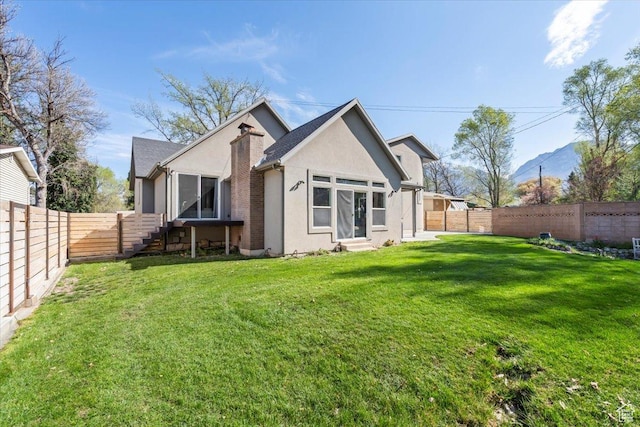rear view of property featuring entry steps, a fenced backyard, stucco siding, and a lawn
