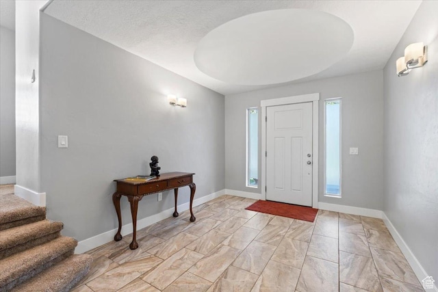 foyer entrance with stairs, marble finish floor, and baseboards