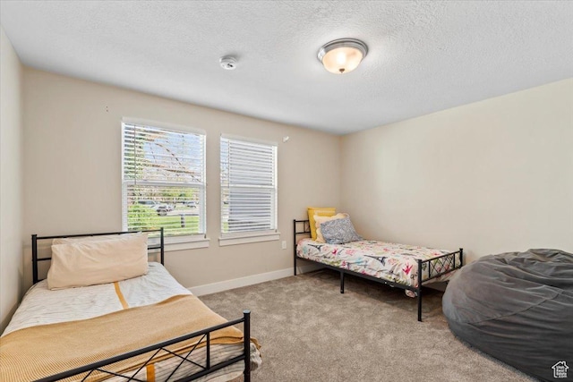 bedroom featuring baseboards, light colored carpet, and a textured ceiling