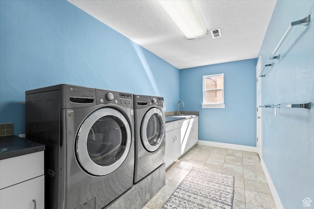 clothes washing area with baseboards, separate washer and dryer, a sink, a textured ceiling, and cabinet space