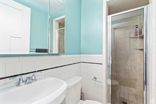 bathroom featuring a shower stall, tile walls, a sink, and toilet