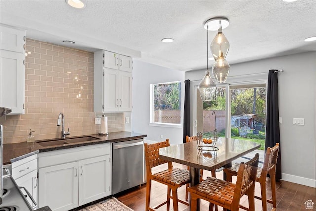 kitchen with a textured ceiling, backsplash, white cabinets, dishwasher, and a sink