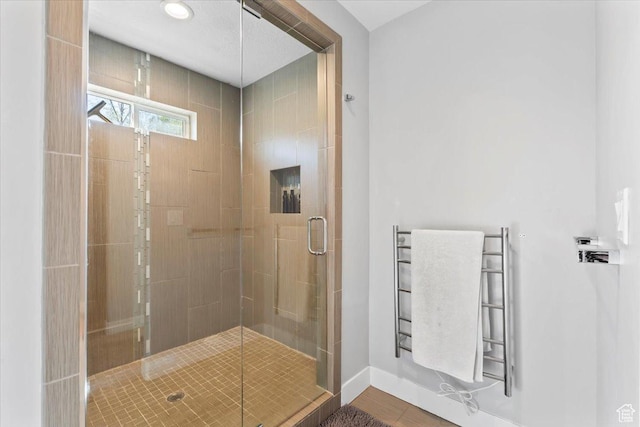 bathroom featuring a shower stall, baseboards, and radiator