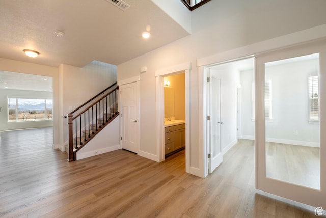 interior space featuring visible vents, baseboards, light wood-style floors, recessed lighting, and stairs