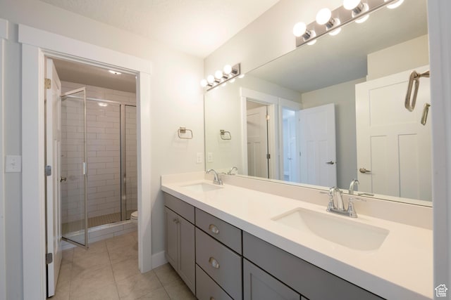 full bath with toilet, tile patterned floors, a sink, and a stall shower