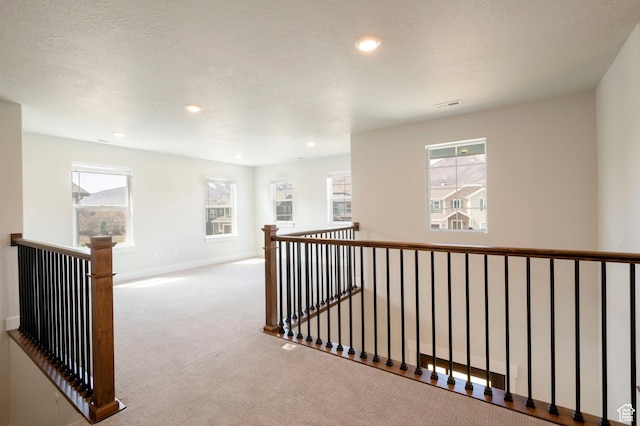 hall with visible vents, baseboards, an upstairs landing, and carpet