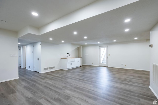 basement featuring indoor wet bar, recessed lighting, visible vents, a sink, and wood finished floors