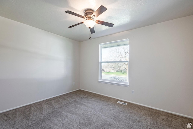 carpeted empty room featuring baseboards, a ceiling fan, and visible vents