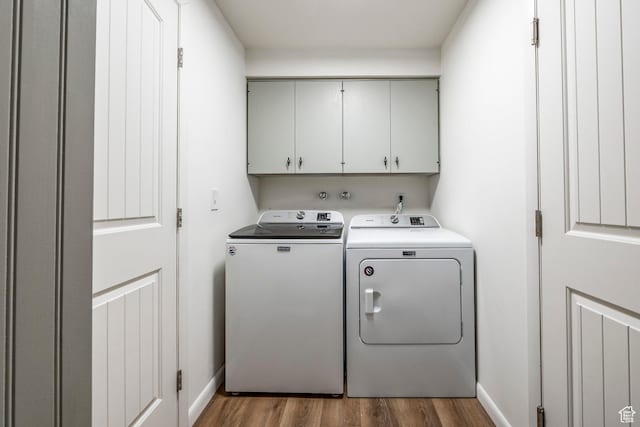 clothes washing area with dark wood-type flooring, washer and clothes dryer, baseboards, and cabinet space