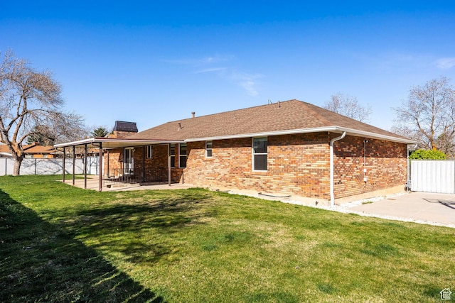 back of house with a patio area, a lawn, fence, brick siding, and roof with shingles