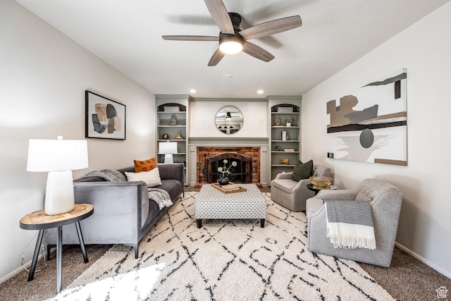 living area featuring baseboards, a ceiling fan, carpet flooring, and a fireplace