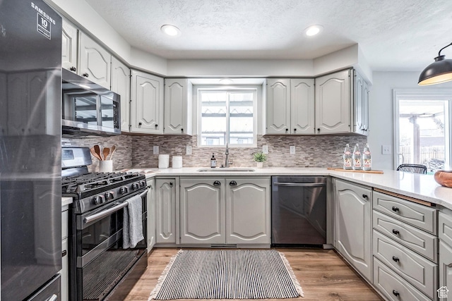 kitchen with stainless steel appliances, tasteful backsplash, a textured ceiling, and a sink