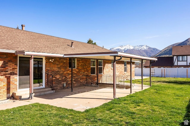 back of property featuring a mountain view, a lawn, fence, a patio, and brick siding