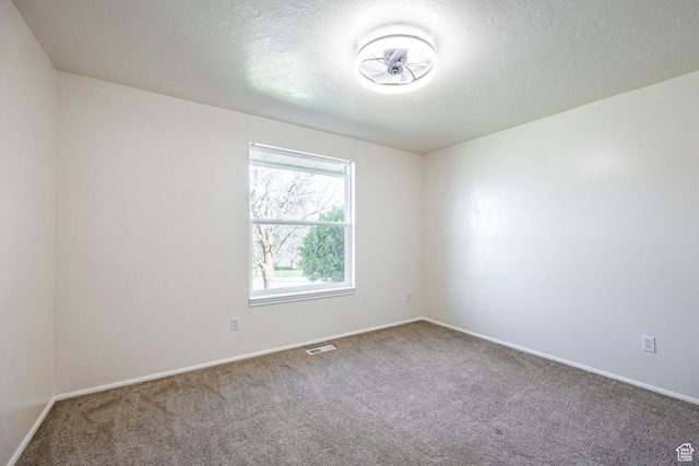 carpeted empty room featuring visible vents, baseboards, and a textured ceiling