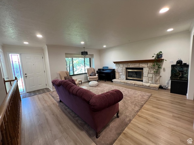 living area with wood finished floors, a fireplace, ornamental molding, and recessed lighting