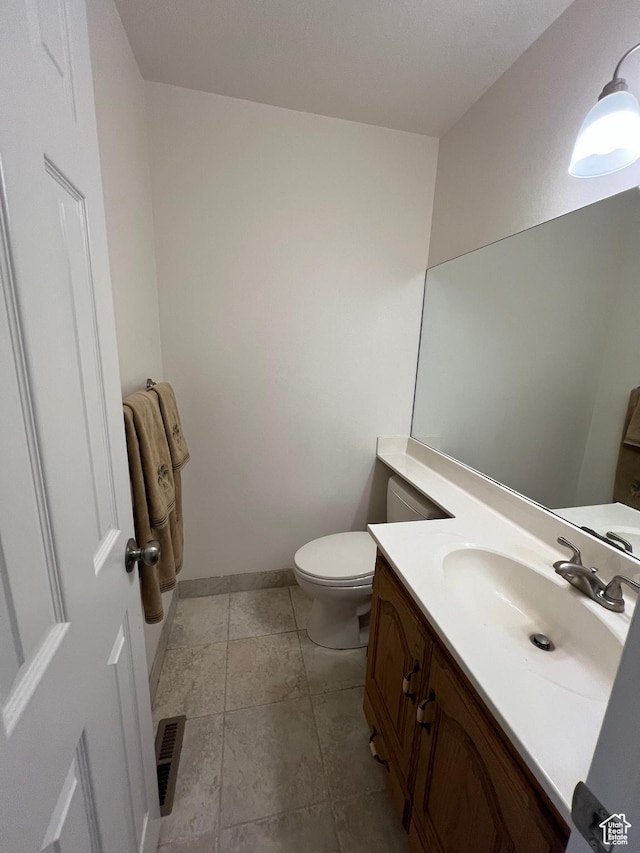 bathroom featuring vanity, baseboards, visible vents, and toilet