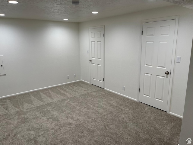 below grade area featuring baseboards, recessed lighting, carpet, and a textured ceiling