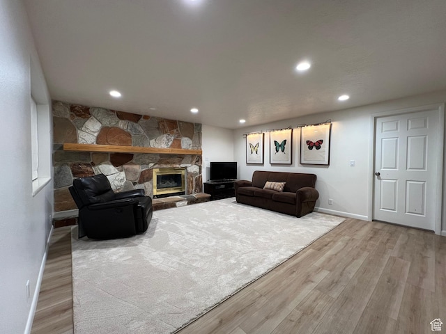 living area with baseboards, a stone fireplace, wood finished floors, and recessed lighting