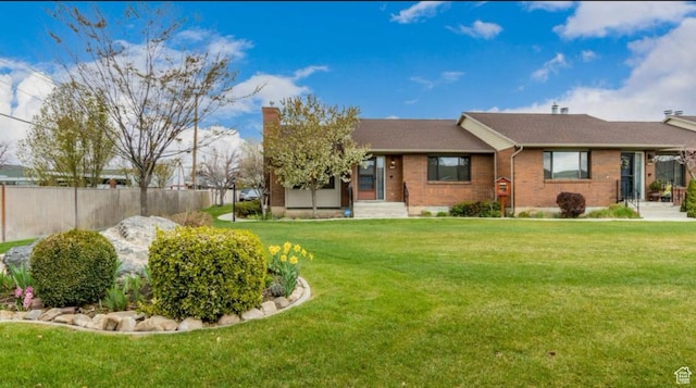 view of front of house with a front yard, brick siding, and fence