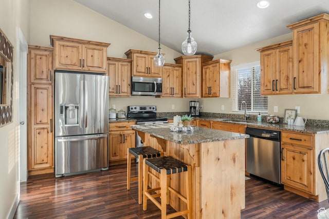 kitchen with a center island, a sink, stainless steel appliances, a breakfast bar area, and lofted ceiling