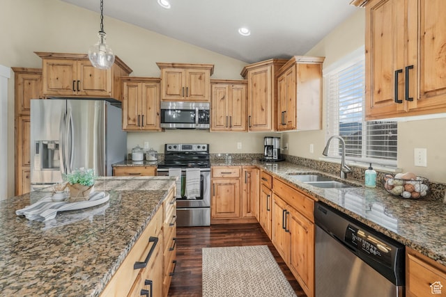 kitchen featuring vaulted ceiling, dark stone countertops, appliances with stainless steel finishes, dark wood-style flooring, and a sink