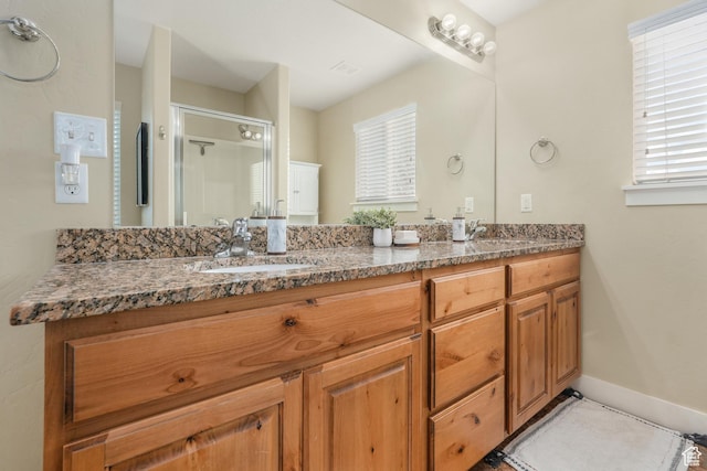 bathroom with a sink, baseboards, a shower stall, and double vanity
