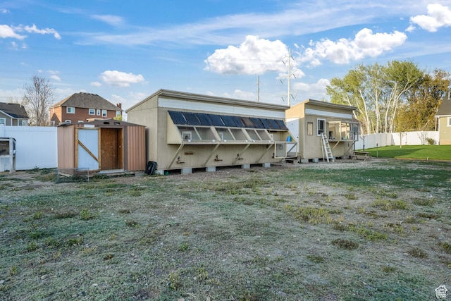 rear view of house featuring a yard, fence, an outbuilding, and a storage unit