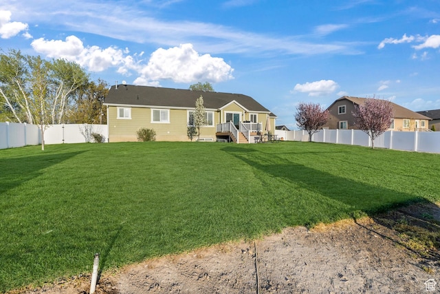 rear view of house featuring a fenced backyard, a deck, and a lawn