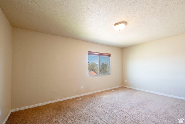 empty room featuring visible vents, baseboards, light carpet, and a textured ceiling