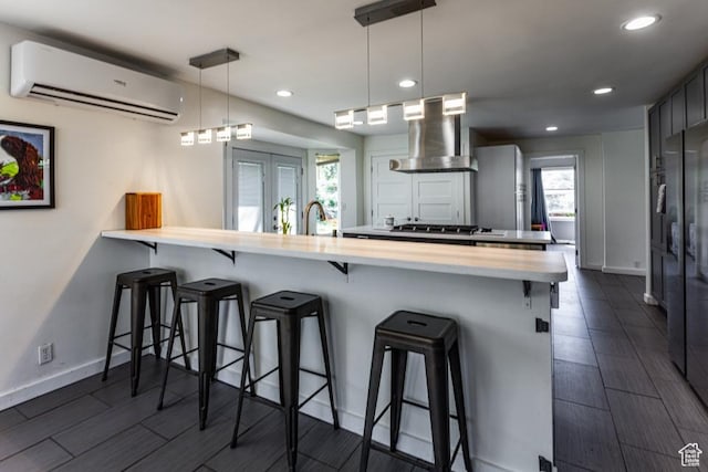 4455 S Aspen Hollow Ln, Holladay, UT 84117 - kitchen with exhaust hood, a peninsula, a breakfast bar, a wall mounted AC, and light countertops